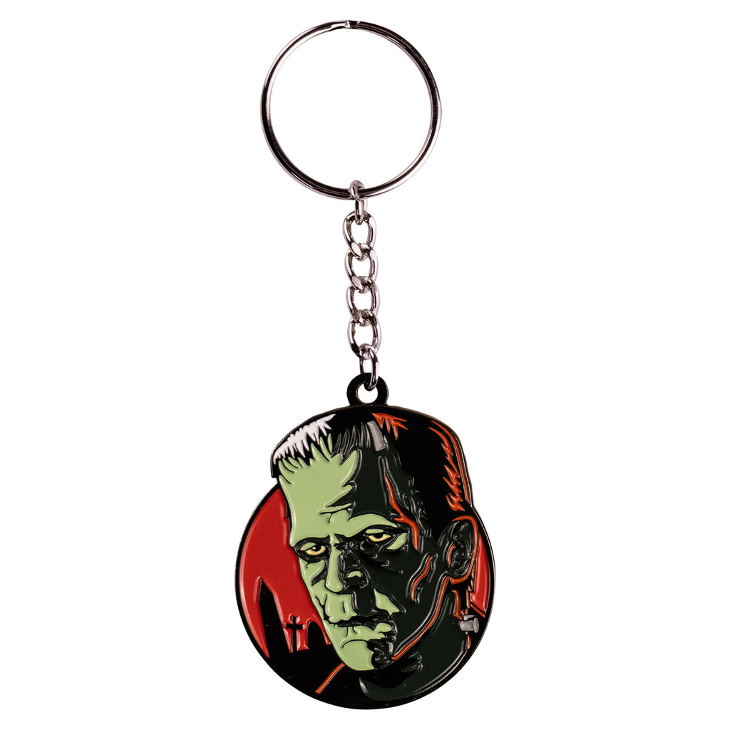  Keychain. Red circle background, gravestone silhouettes. Green Frankenstein face and neck, black hair, orange highlights, metal bolt on neck. attached to silver chain and keyring