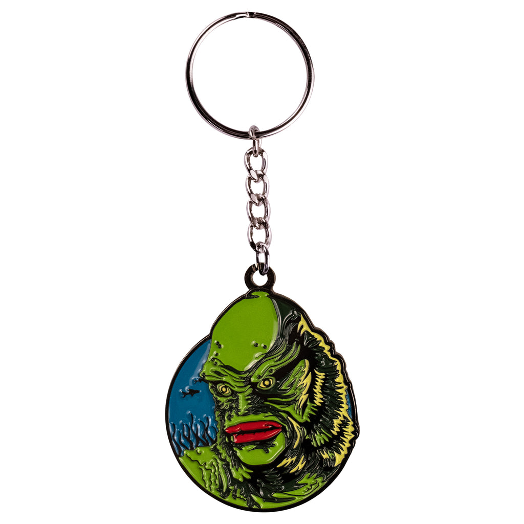 Keychain. Blue circle background, black outline, silhouette of fish and seaweed in background. Green fishman face, red lips yellow eyes. attached to silver chain and keyring