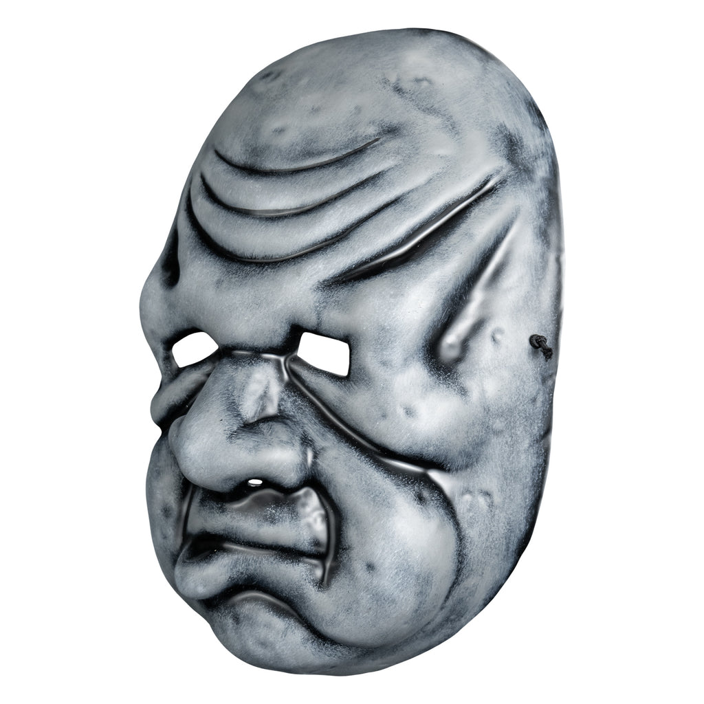 Mask, left view. Black and white toned face mask. Bald, wrinkles on forehead, no eyebrows, bags under small eyes, short fat nose, heavy jowls, mouth with misshapen lower lip.