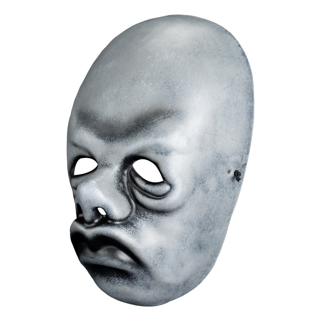 Mask, left view. Black and white toned face mask. Bald, no eyebrows, bags under eyes, pug nose, mouth in a frown with prominent lips.