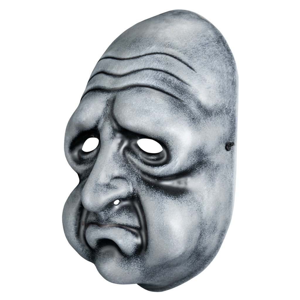 Mask, left view. Black and white toned face mask. Bald, wrinkles on forehead, no eyebrows, bags under eyes, long nose, round cheeks and chin, mouth in a frown with prominent lower lip .