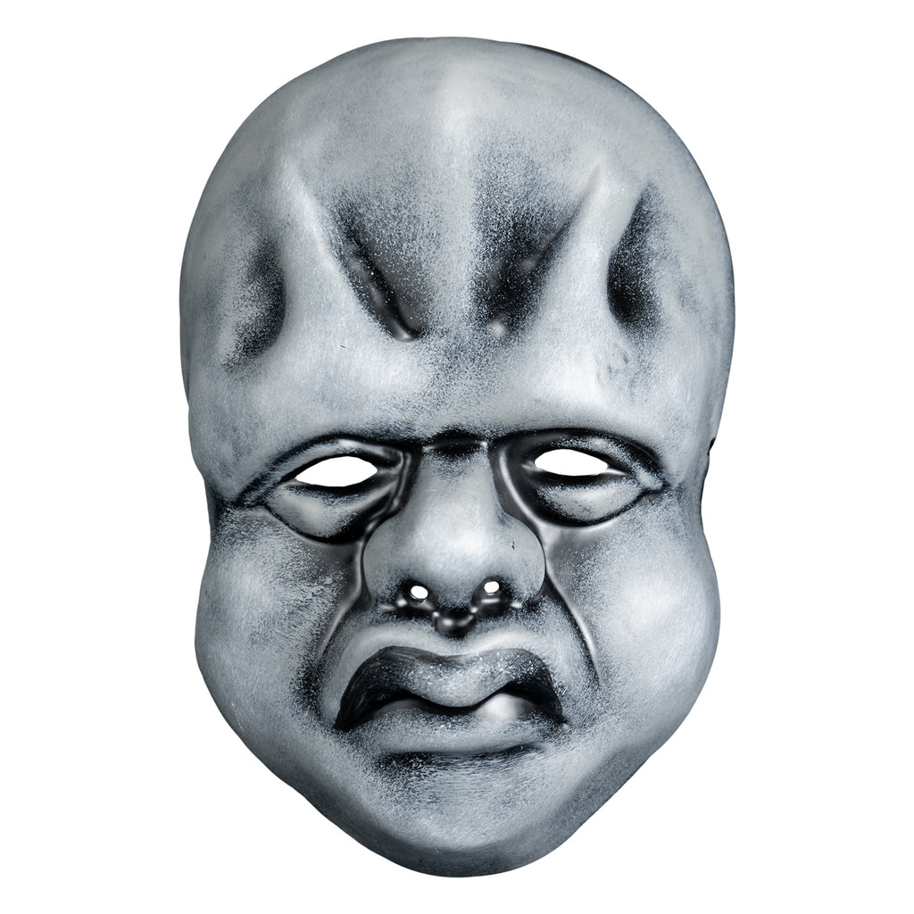 Mask, front view. Black and white toned face mask. Bald, ridges on forehead, no eyebrows, bags under small eyes, short fat nose, heavy cheeks and jowls, mouth with prominent frowning lips.