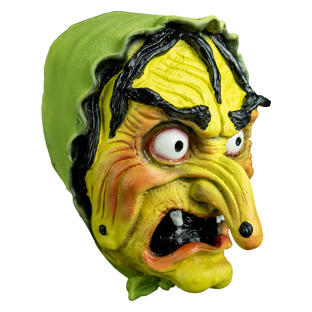 Mask right view. yellow-green wrinkled flesh, wearing a green bonnet, stringy black hair and eyebrows, large red-rimmed white eyes, long pointed nose with a black wart, open grimacing mouth showing gapped white teeth.