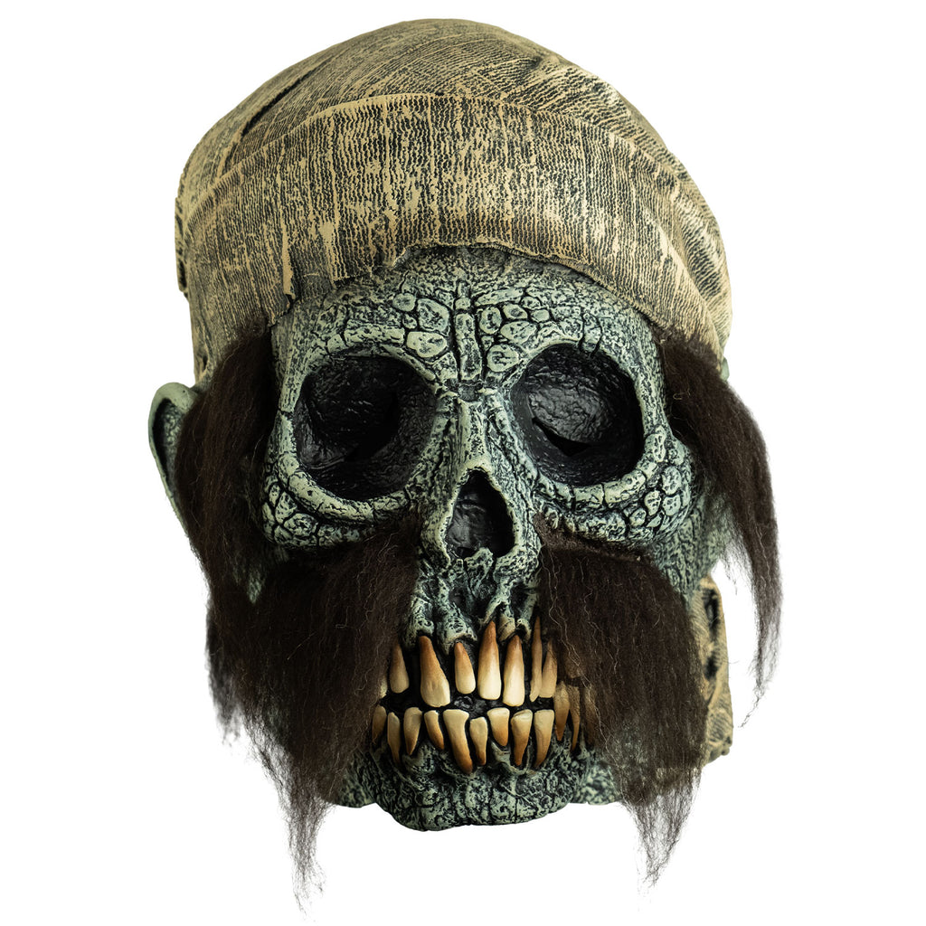 mask, front view. dirty off-white scarf on head hanging down to neck. Empty eye sockets,  long brown sideburns and mustache.  Cracked gray skull face with ears, long yellow teeth. 