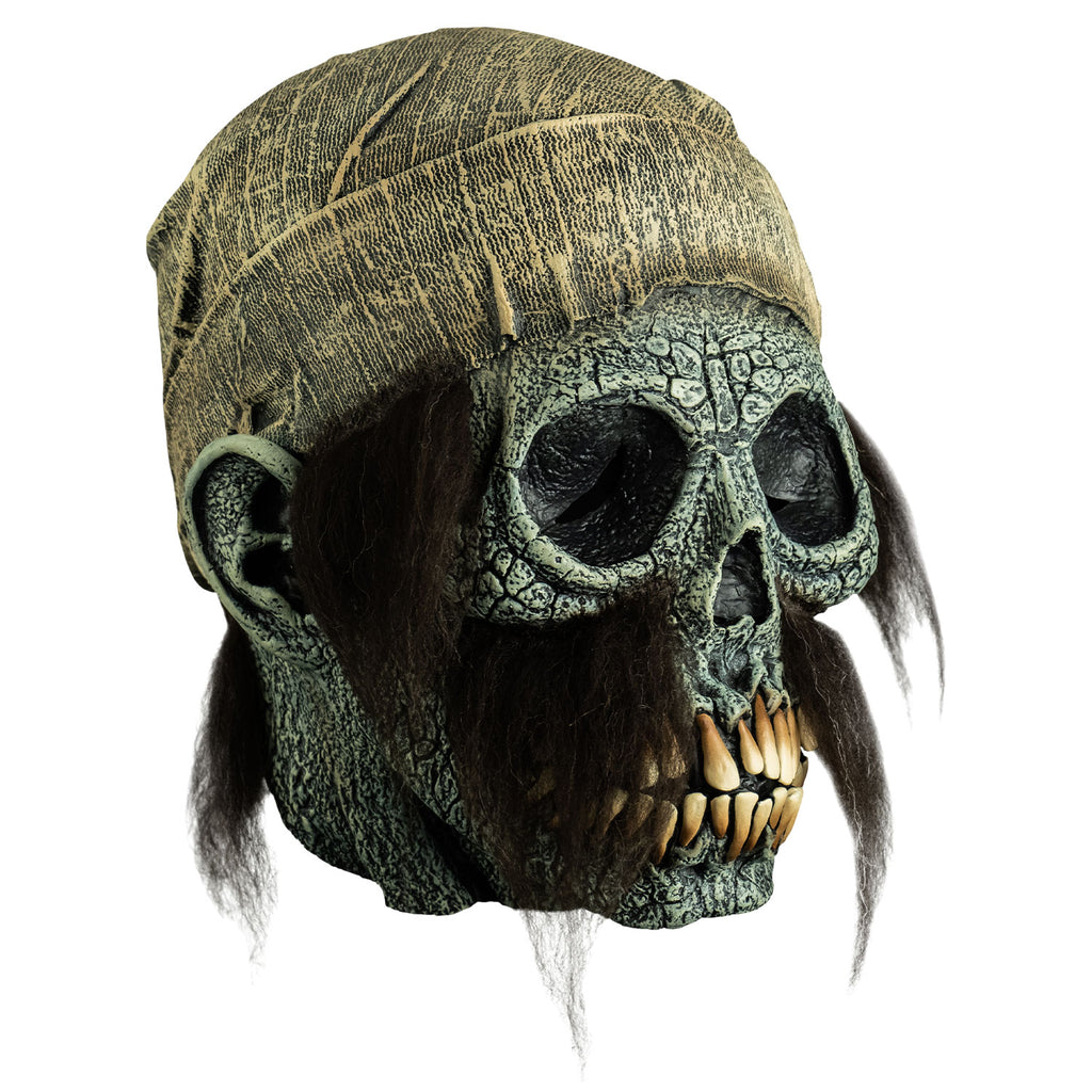 mask, right view. dirty off-white scarf on head hanging down to neck. Empty eye sockets, long brown sideburns and mustache. Cracked gray skull face with ears, long yellow teeth.