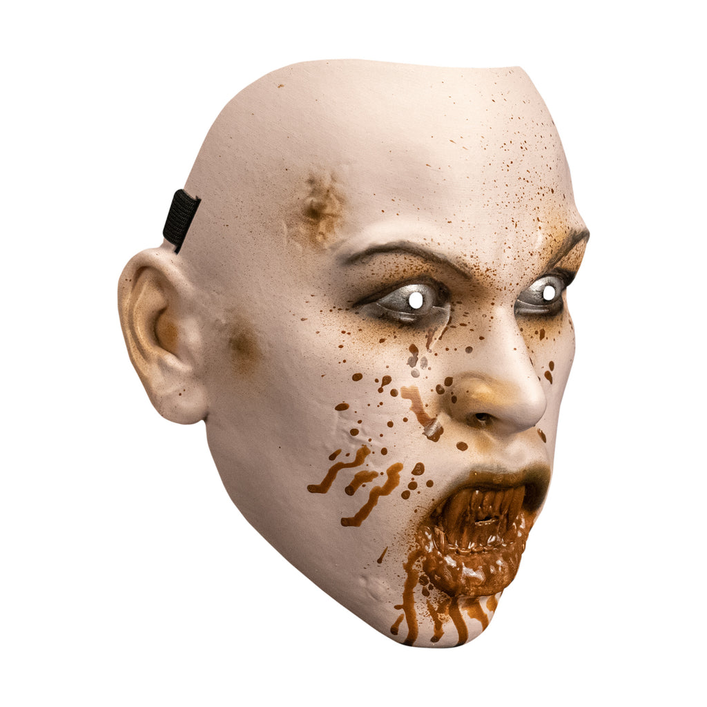 Plastic mask. Right side view. pale skin, blood spattered face. brown arched eyebrows, black-rimmed white eyes. mouth with lips open showing sharp bloodstained teeth, blood dripping down chin.