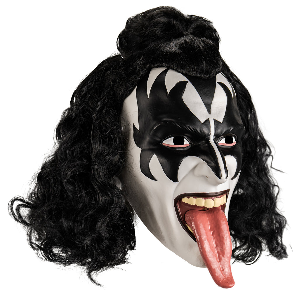 Kiss plastic mask right view. Black curly hair, front half in a bun at the forehead. White face, black painted widow's peak on forehead, black painted demon wings over eyes forehead and cheeks. Black lips, mouth wide open showing upper teeth and long tongue hanging out.