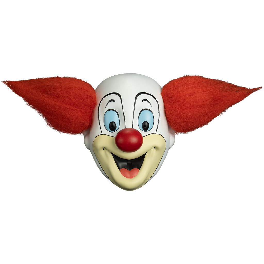 Bozo clown mask, front view.  White face, tuft of red hair on each side of head.  Painted black lines around eyes and small black eyebrows, large pale blue eyes.  Red round nose.  tan area around mouth.  mouth open in a smile showing red tongue.