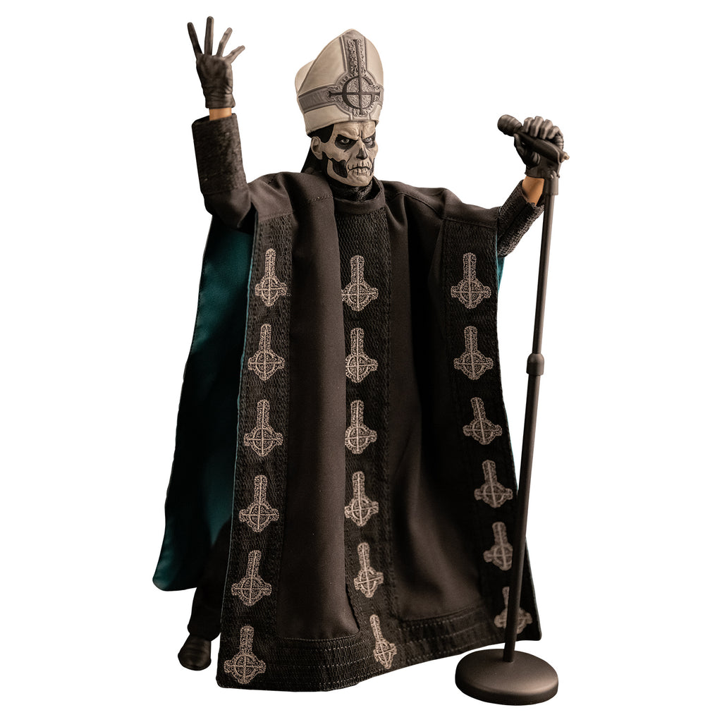 White background. Figure and accessories. Black and white skull-like face wearing black and silver, tall hat adorned with black inverted cross with semi circle that looks like a G. wearing black floor-length robe green on the inside adorned with several white inverted crosses, with semi circle that looks like a G. black gloves and black boots. Holding black microphone and stand in left hand