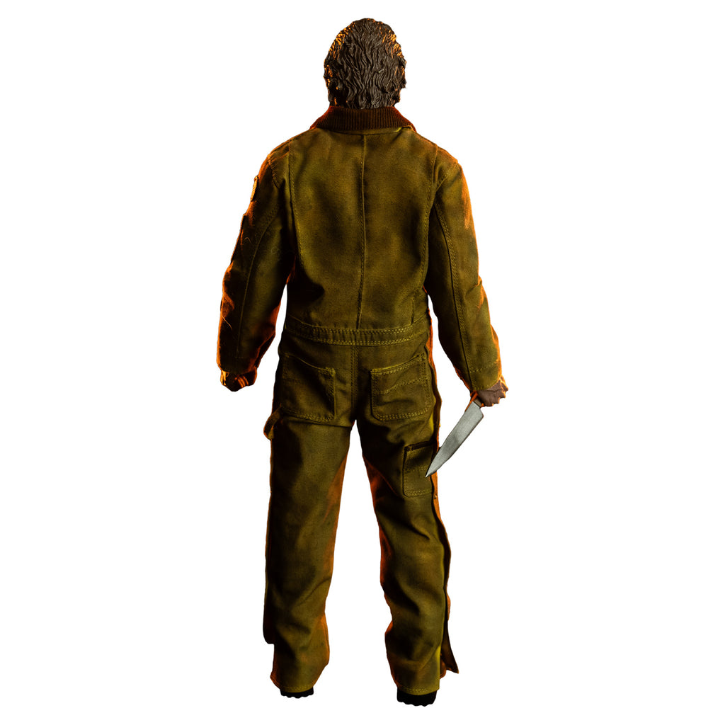 Back view, dramatic lighting, Michael Myers 1:6 scale action figure. Wearing Halloween 2007 mask head turned to the right, tan coveralls, brown boots. holding kitchen knife in right hand at his side, left hand in grabbing position at side.