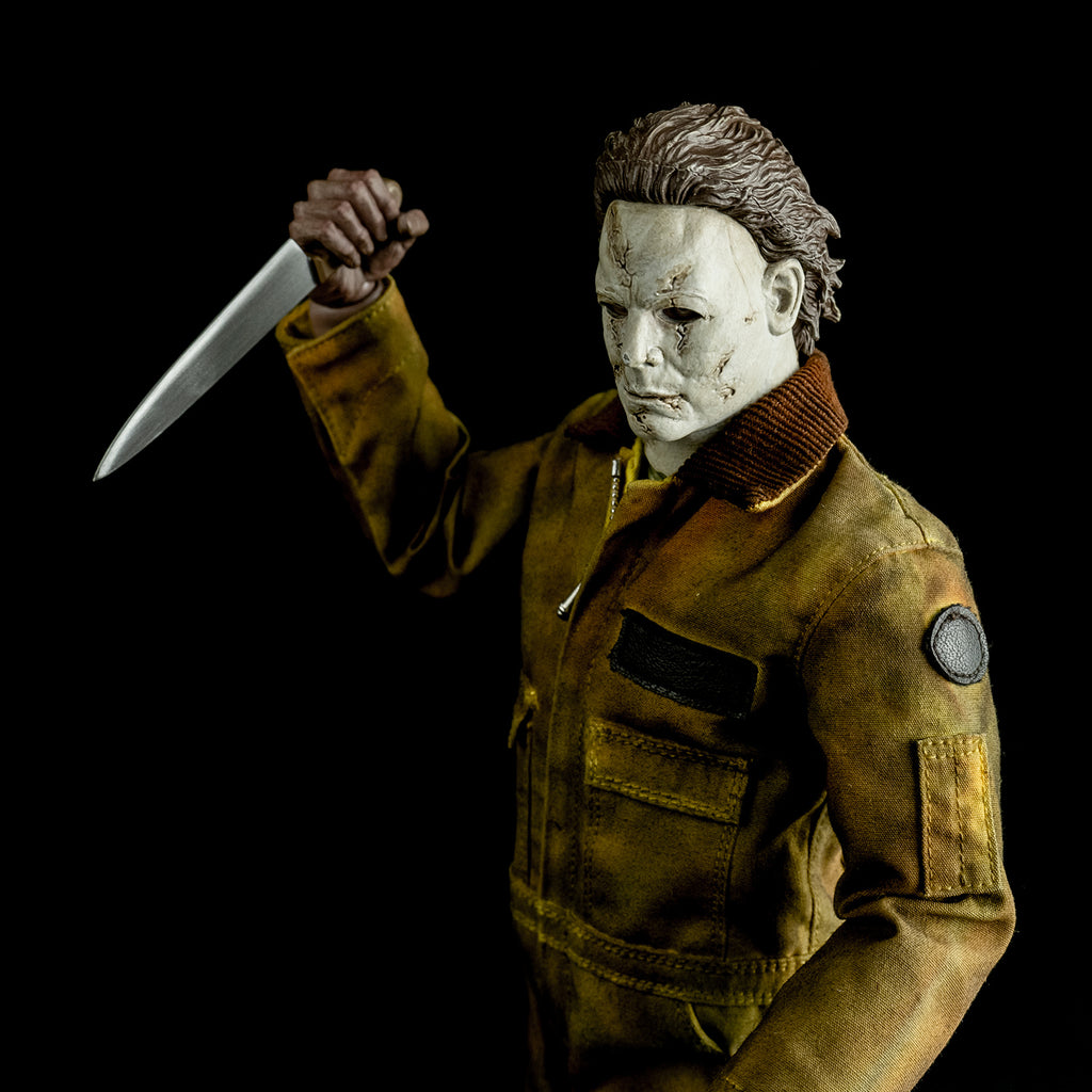 close up, slight overhead left view, above waist. Dramatic lighting. Michael Myers 1:6 scale action figure. Wearing Halloween 2007 mask, tan coveralls. holding kitchen knife in right hand raised above shoulder.