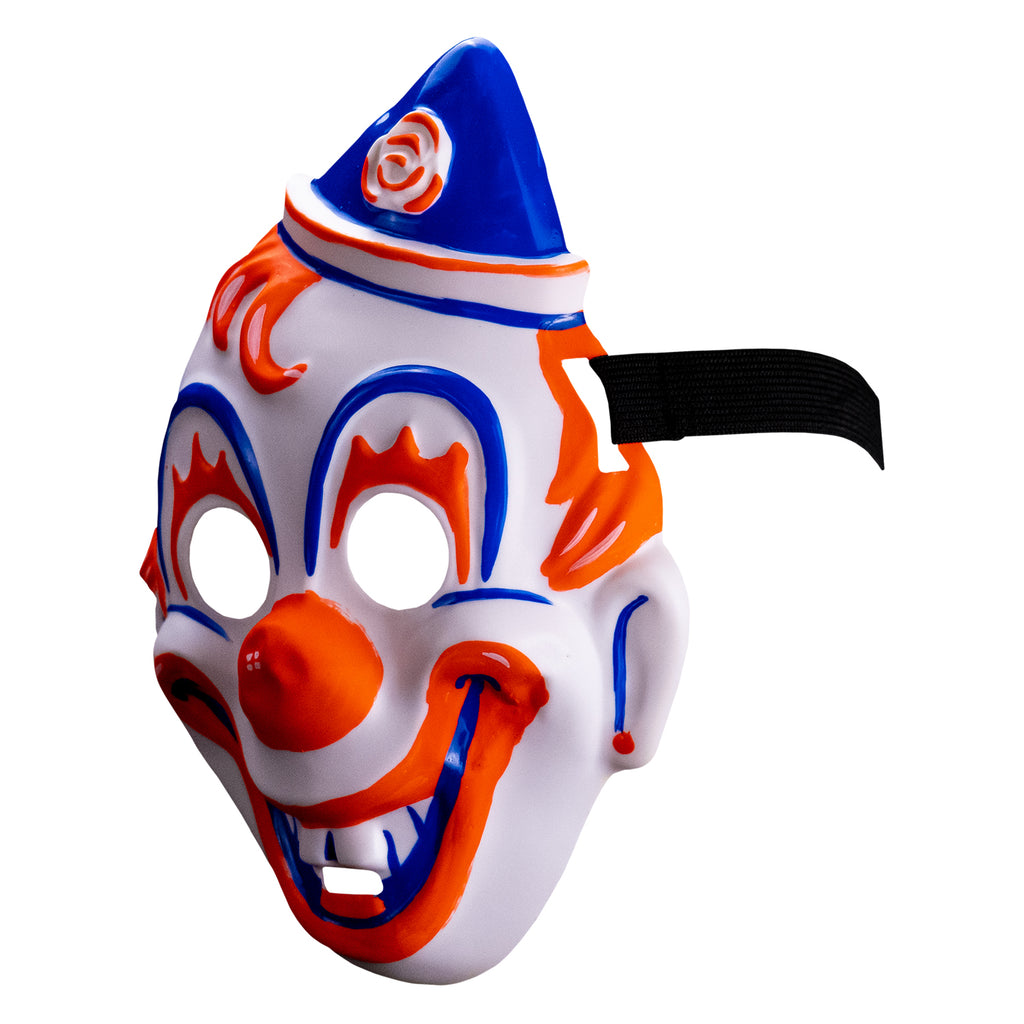 Face mask, left side view. white clown face, blue white and orang triangular hat tipped to the left . orange painted hair. Blue arches around eyes, orange painted eyelashes, blue lines on cheeks and ears, orange dots on earlobes, large orange clown nose. Orange and blue clown mouth in a large smile showing teeth. Black elastic strap at temples