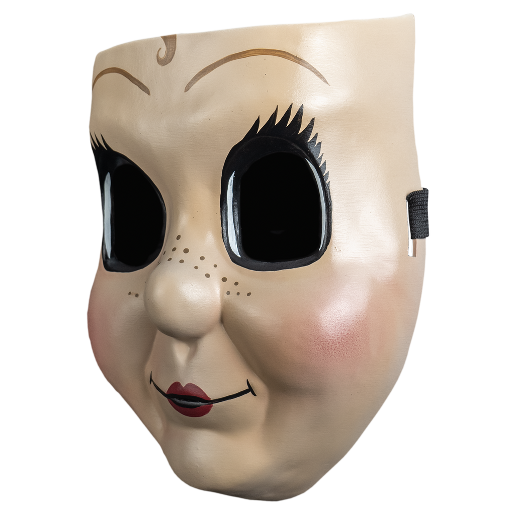 Plastic face mask, left view.  Dollface, Small light brown curly painted in the center of the forehead, large empty black eyes with spiky eyelashes. Thin brown eyebrows. Freckles on nose and cheeks, smiling mouth with small red lips. Plump pink cheeks.