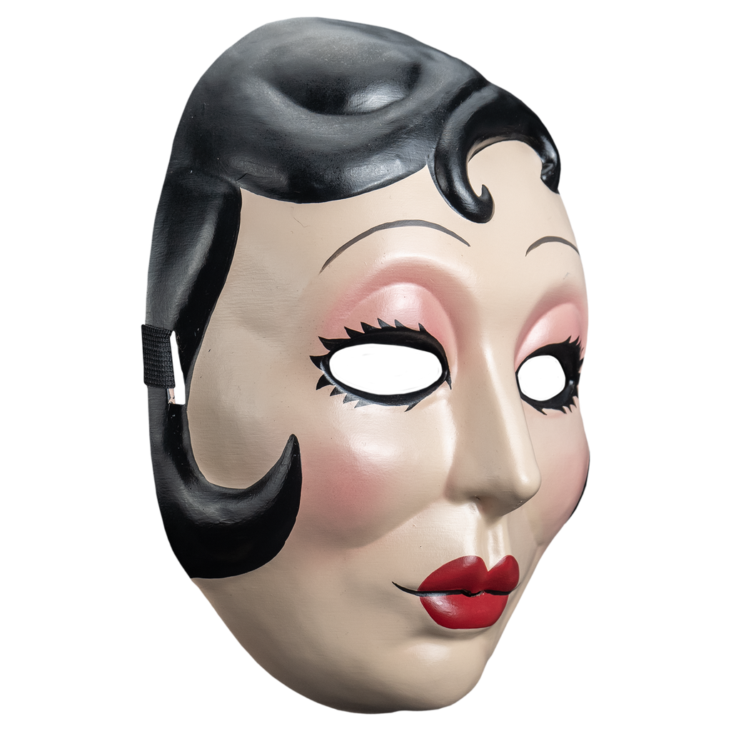 Plastic face mask, right view. Woman's face, short black hair with curl on right side of forehead and at cheeks. Thin penciled eyebrows, empty eye holes, spiky black eyelashes, pink eye shadow. Small round red lips.