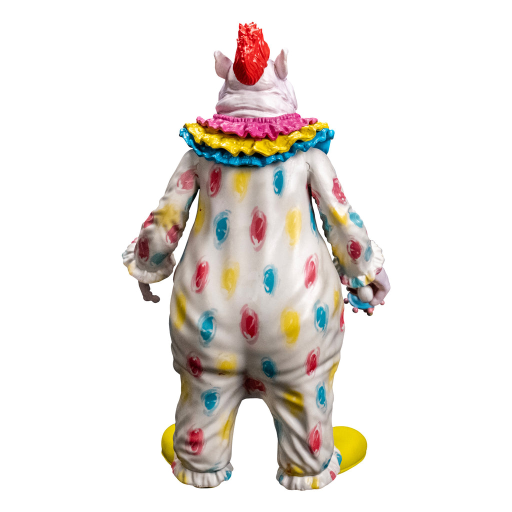 Figure, back view. Lumpy and wrinkly skin with several flesh folds on neck, large pointed ears on side of head. White skin, red hair on top. wearing white clown suit with pink, blue and yellow circles on it. Pink, yellow and blue ruffles at neck, ruffled at wrists and ankles. White hands, right hand holding ray gun. Large yellow shoes.