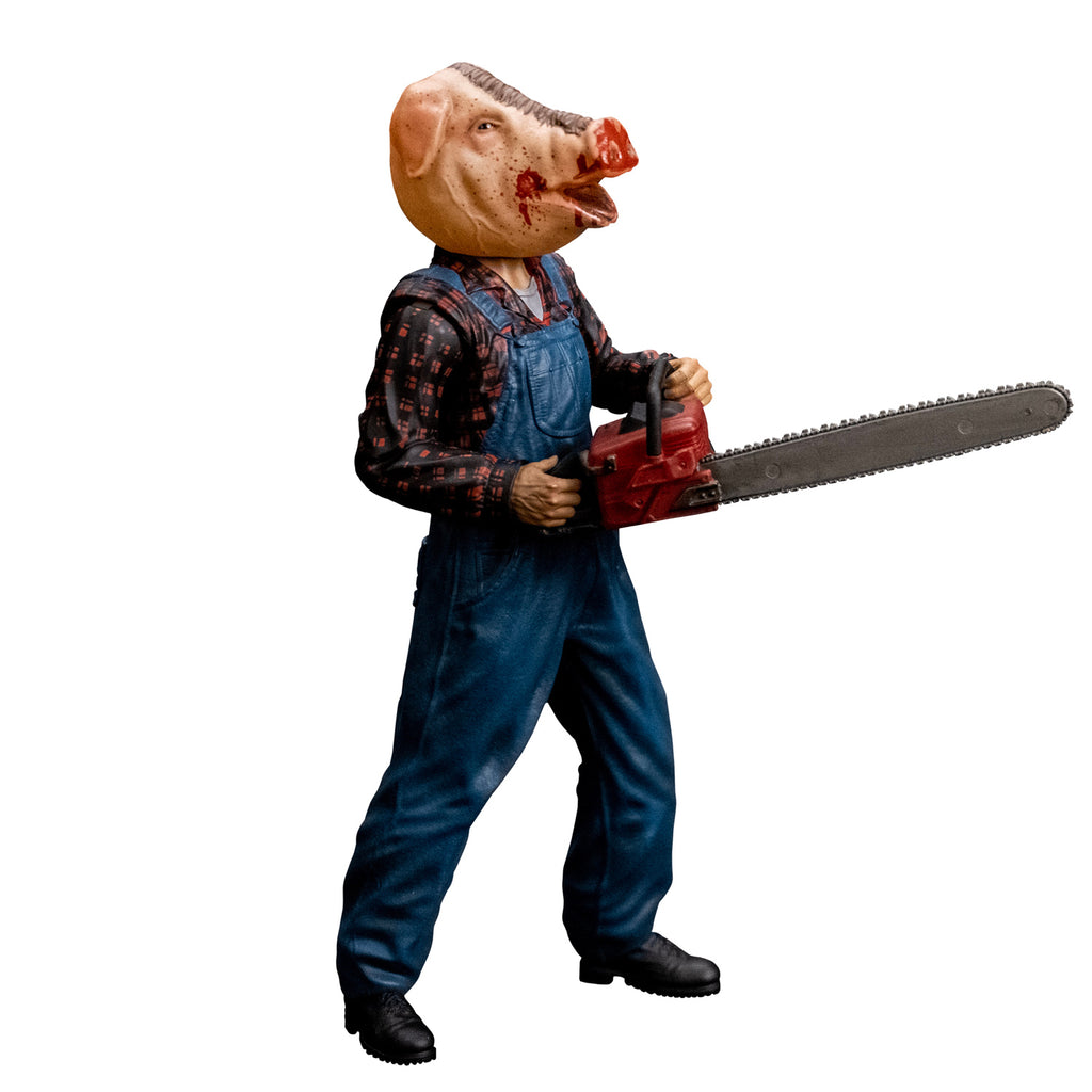 8 inch figure, right side profile view. Person with bloodied pig head mask, mouth open. Wearing flannel print shirt, blue overalls, black boots. Holding red chainsaw with both hands.