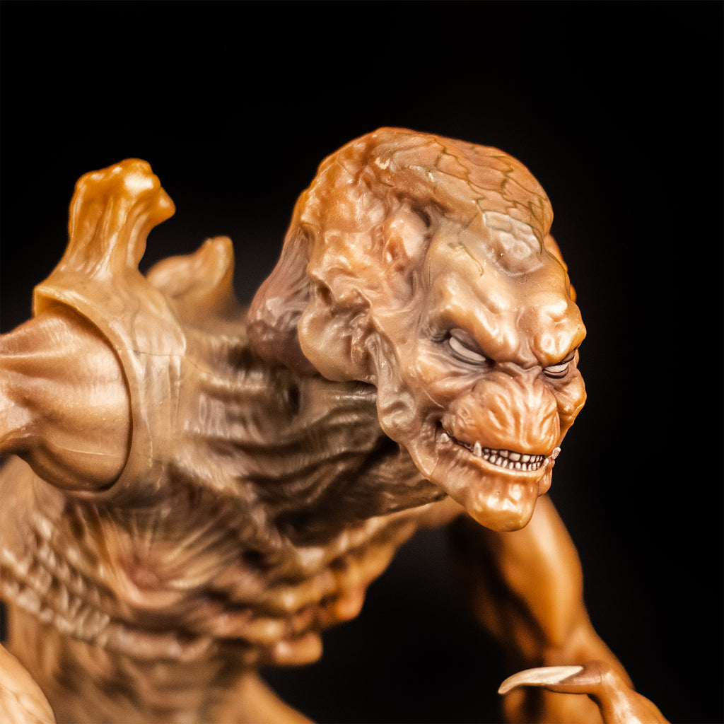 Black background, slight right close-up view, detail of face. Pumpkinhead 8" scale figure. Pale orange tan creature with enlarged upper head. White eyes, animal-like muzzle, mouth showing sharp yellow teeth. Bony with defined muscles, protrusions on shoulders.
