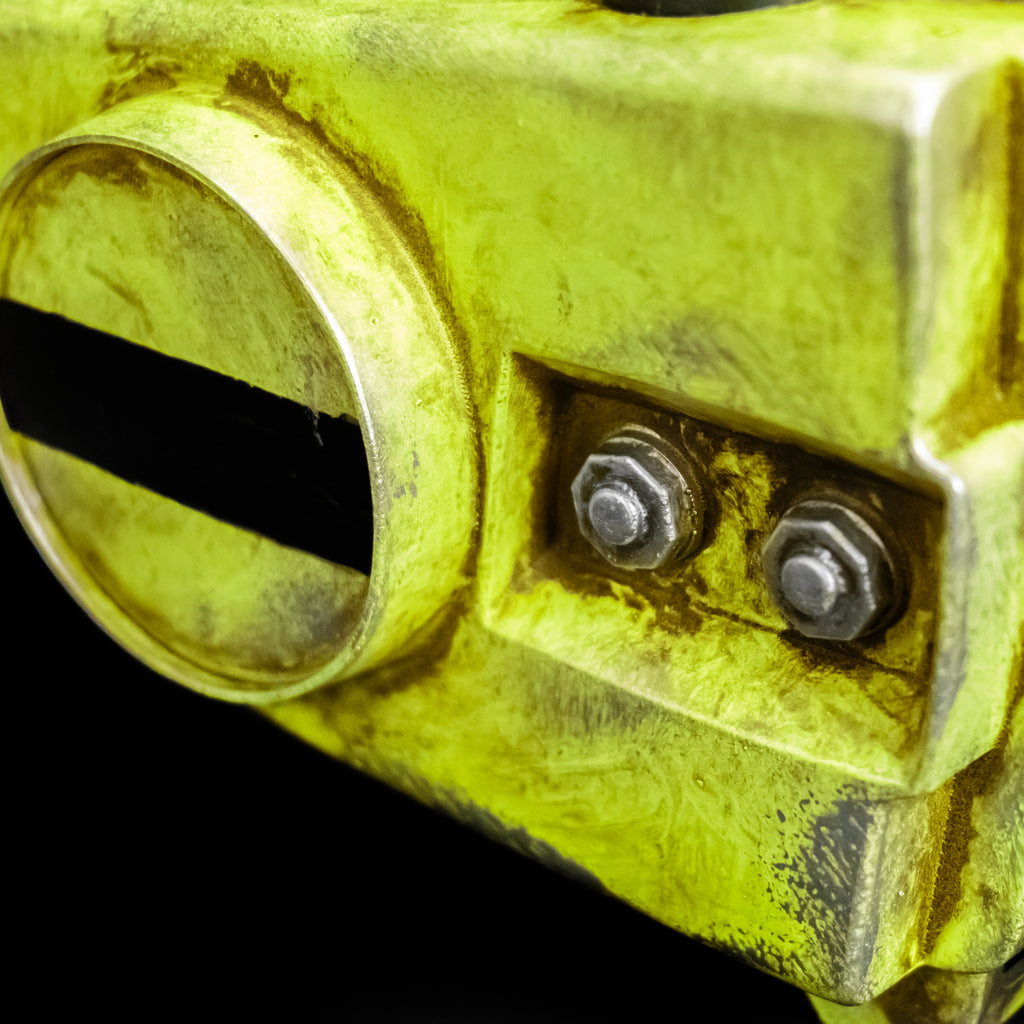 Black background. Chainsaw prop. Close-up view of side showing silver nuts on bolts. Distressed weathered yellow body.