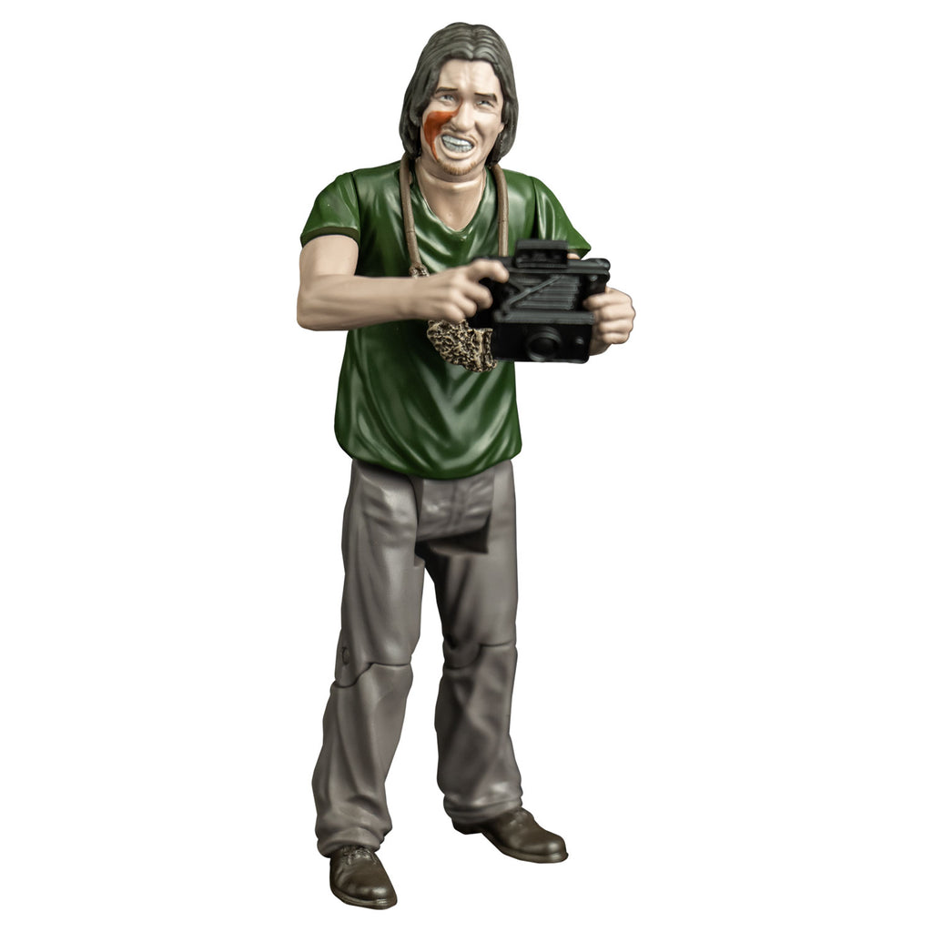 Action figure, front view. man with mid-length brown hair, blood on right cheek, mouth with lips open showing teeth. handmade pouch hanging around his neck. wearing a green t-shirt, gray pants and brown shoes. Holding a vintage camera in his hands at chest level.