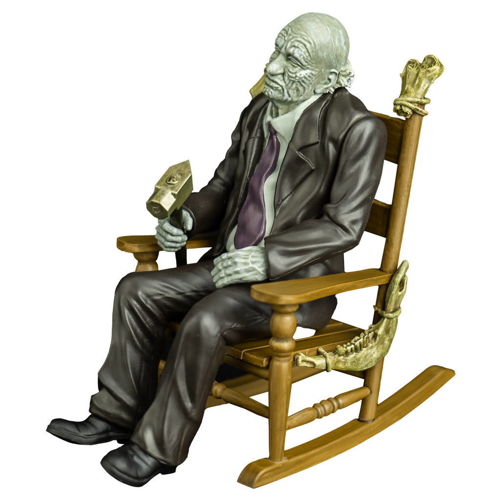 Grandpa figure, left side view. old man, gray skin, bald, gray skin, wearing a suit and tie, holding a hammer in right hand, sitting in rocking chair with bones tied to the back, and sides