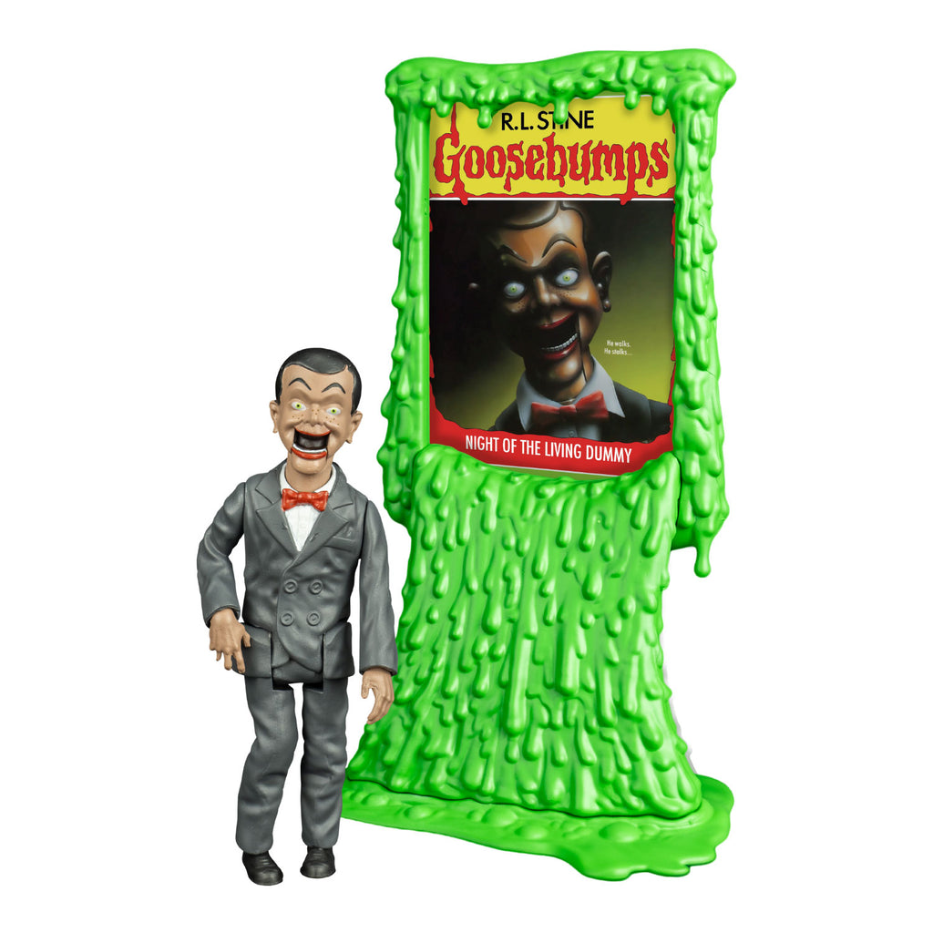 Goosebumps slappy figure, front view, Ventriloquist dummy face, dark hair and eyebrows, large yellow green eyes, bright red lips, open hinged dummy mouth showing teeth. white dress shirt, red bow tie. Gray suit coat and pants. black shoes. shown next to Green slime book card stand