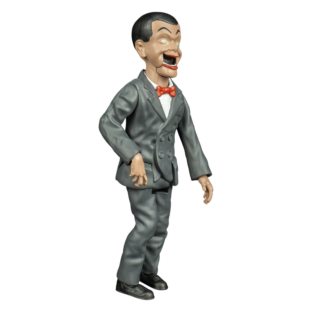 Goosebumps slappy figure, right view, Ventriloquist dummy face, dark hair and eyebrows, large yellow green eyes, bright red lips, open hinged dummy mouth showing teeth. white dress shirt, red bow tie. Gray suit coat and pants. black shoes.