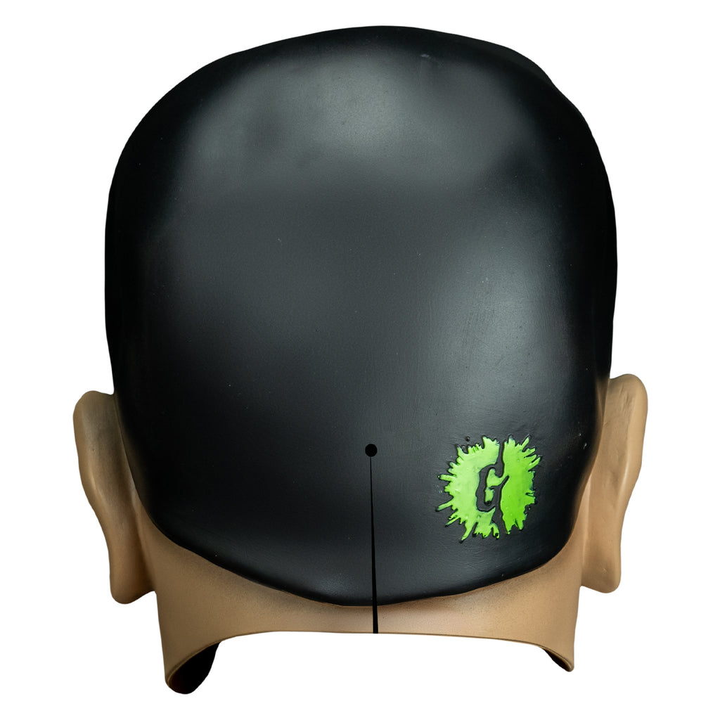 mask back view. Ventriloquist dummy head, black hair.  slit at bottom center, embossed G logo in green splatter spot.