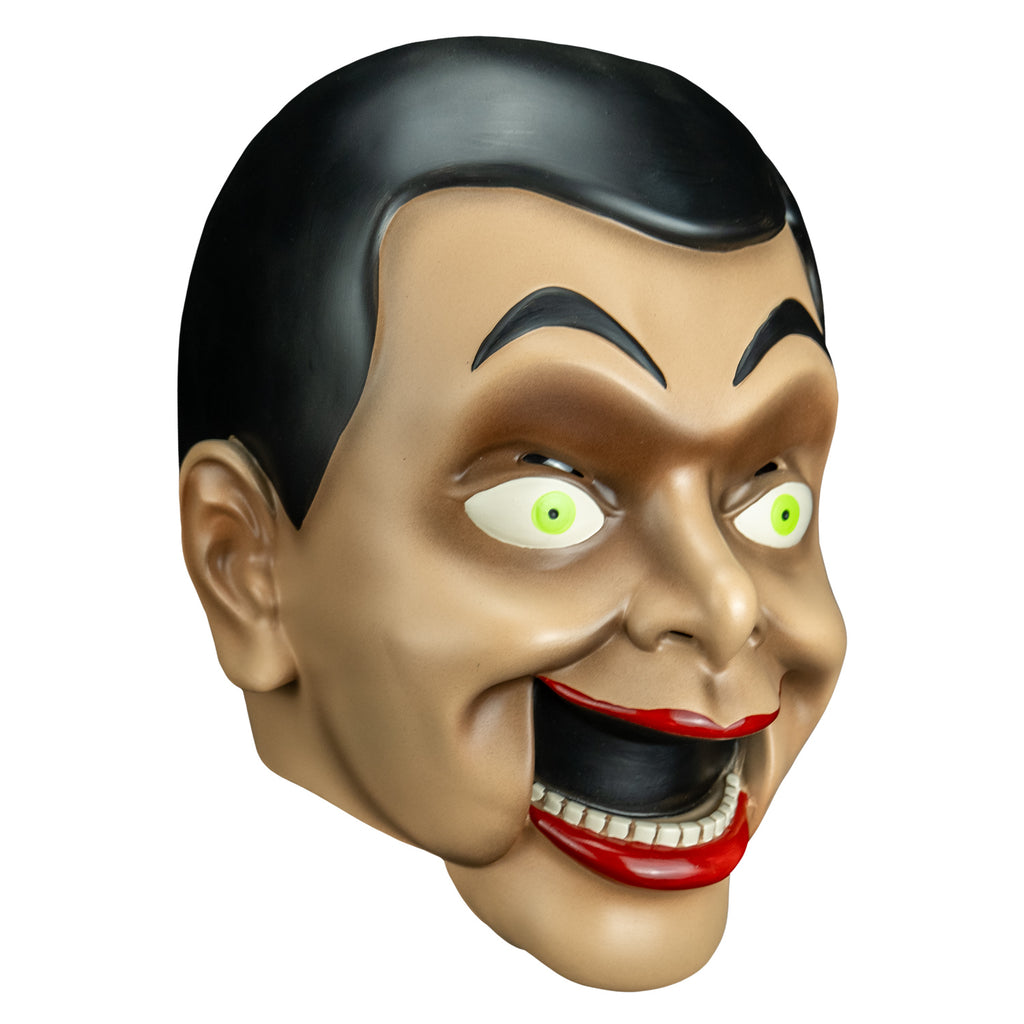 mask left side view. Ventriloquist dummy face, black hair and eyebrows, large yellow green eyes, bright red lips, open hinged dummy mouth showing teeth.