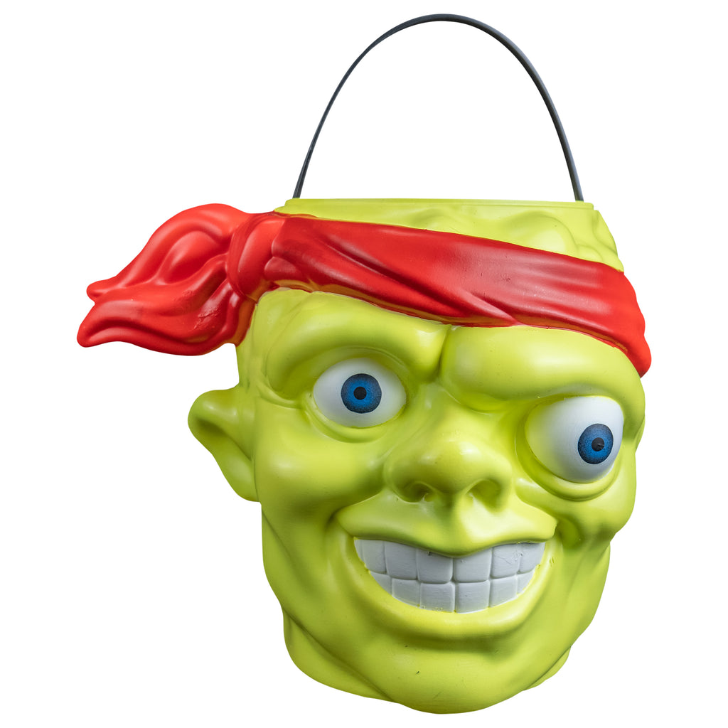 Candy pail, front view. Bald head, green lumpy flesh, with red-orange headband tied around forehead. Misaligned blue eyes, crooked nose. Lips open showing large teeth. Green handle at top.