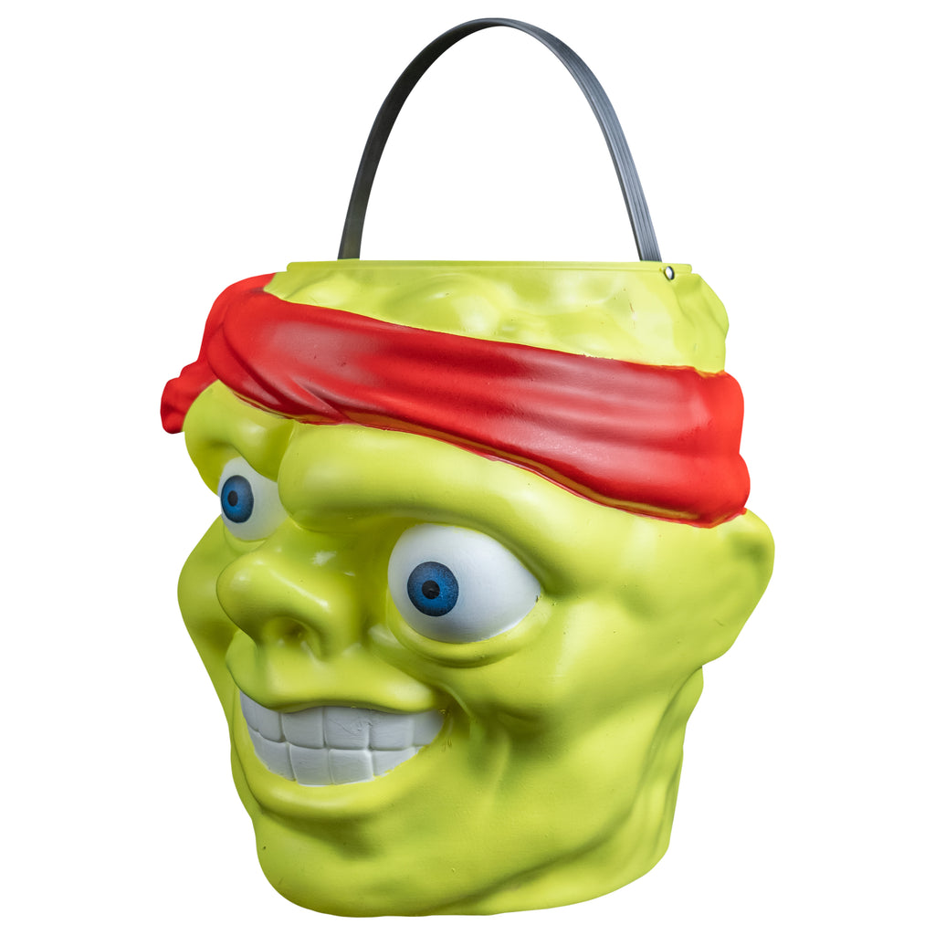 Candy pail, left side view. Bald head, green lumpy flesh, with red-orange headband tied around forehead. Misaligned blue eyes, crooked nose. Lips open showing large teeth. Green handle at top.