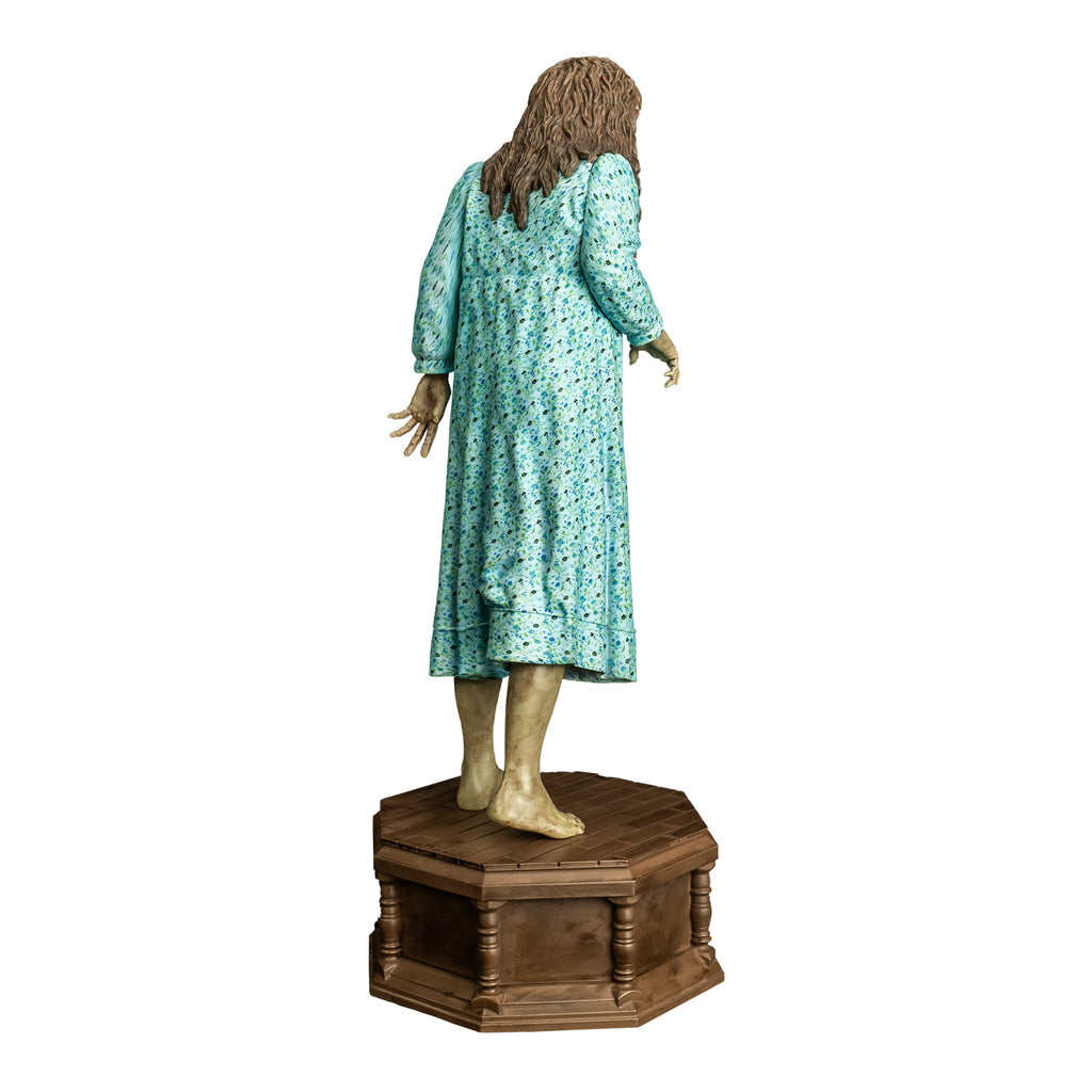 Statue, back view. Girl with light brown, wavy hair.  Wearing light blue flowered nightgown. bare feet. standing on wood-look octagonal base.