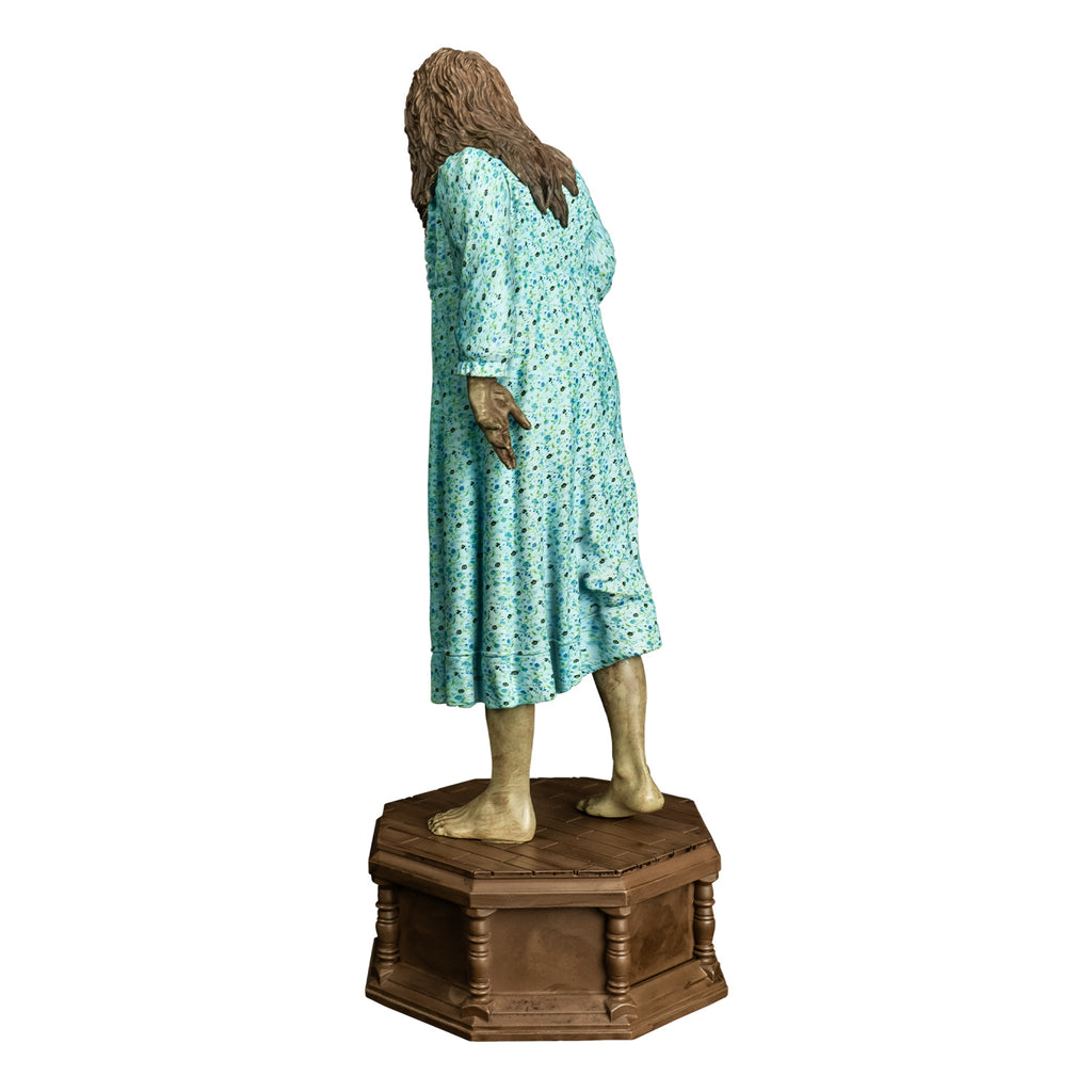 Statue, back view. Girl with light brown, wavy hair. Wearing light blue flowered nightgown. bare feet. standing on wood-look octagonal base.