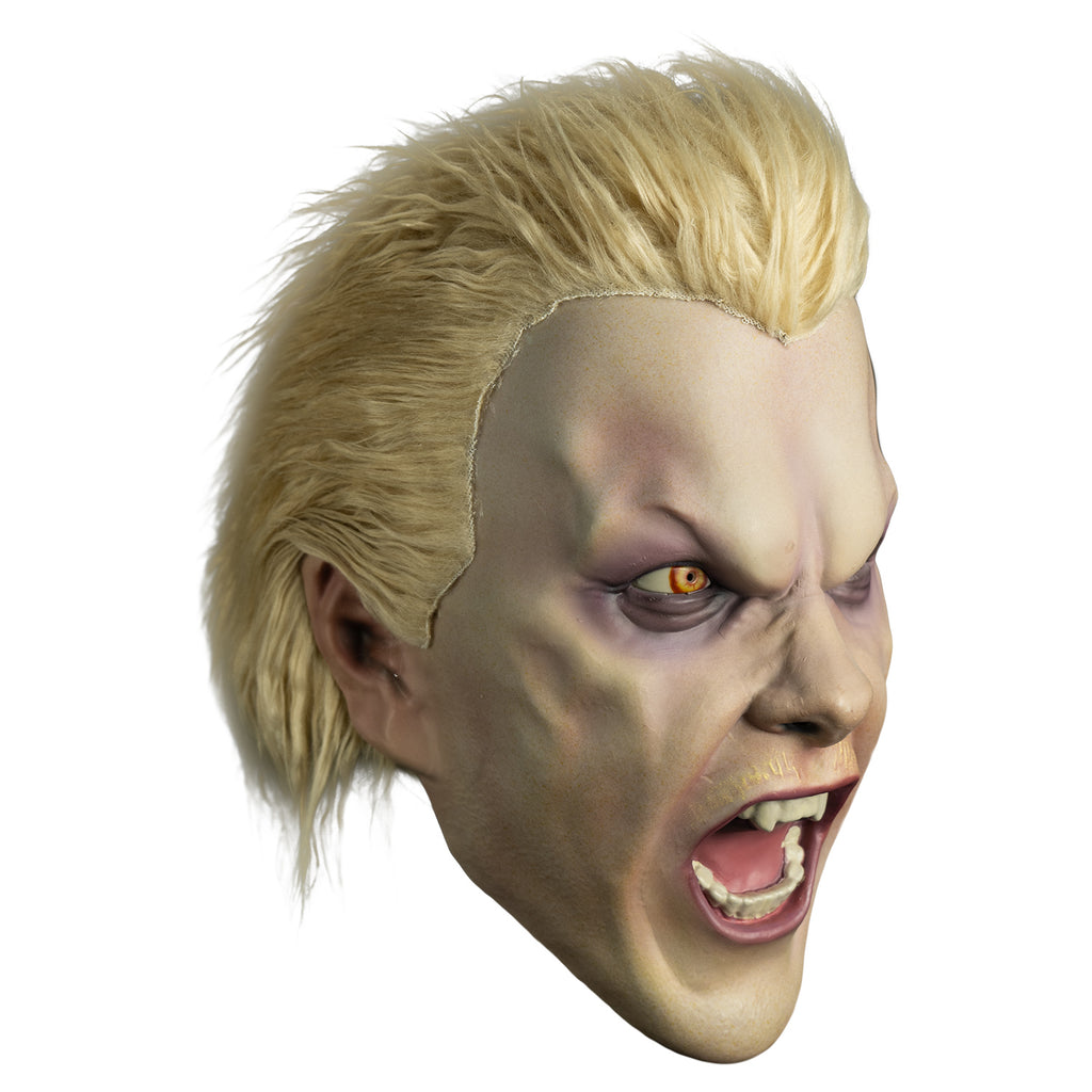 Mask, right view.  Light blond hair, slight mullet.  Furrowed brow, no eyebrows, dark circles under yellow eyes, long black earring in left ear, pale thin blond mustache,  mouth open in a snarl showing pink tongue and white teeth, fangs on either side of top two center teeth