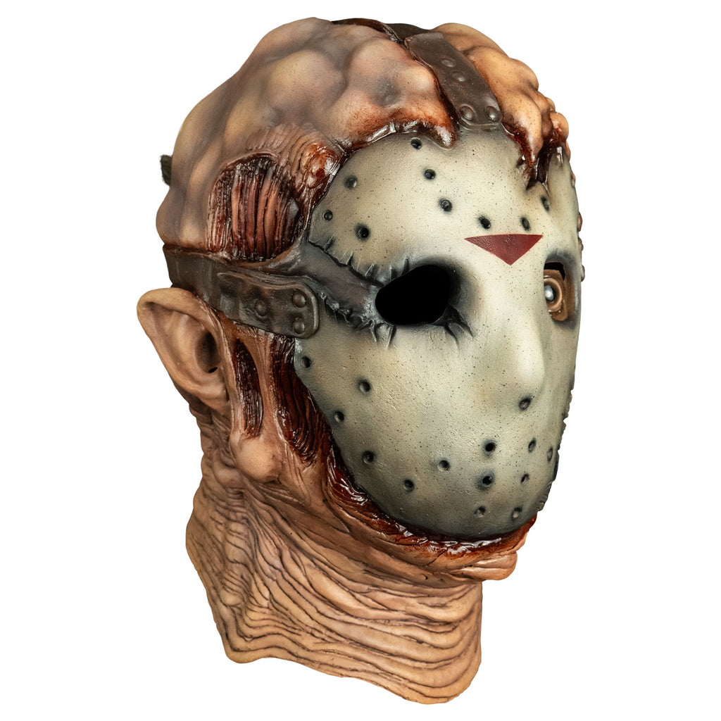 Mask, right side view. lumpy and damaged flesh on top of head, tattered, dirty hockey mask on face, brown straps at top and sides of head from forehead and temples going back. Right empty eye socket, Brown, left eye open, wrinkled and sagging flesh around chin and neck.