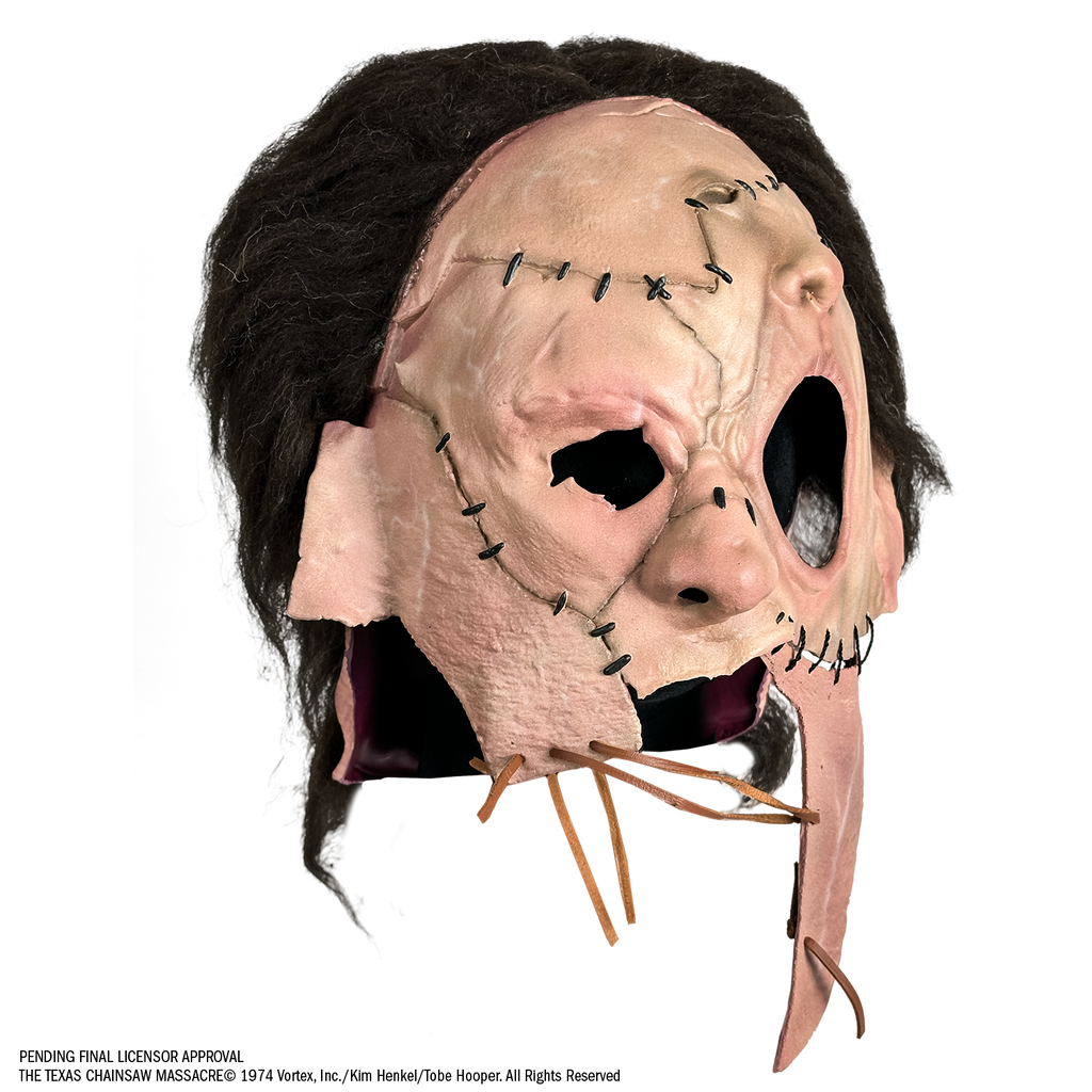 Mask, right view, short, dark brown, bushy hair, skin is sewn together, stitches around forehead, cheeks and ears, patch of skin over left eye and forehead is shaped like a nose and mouth. Lower face is open below nose with leather stitching across.