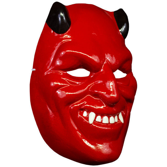 Plastic mask, right side view. Bright red, black horns, grinning mouth with white teeth and fangs.