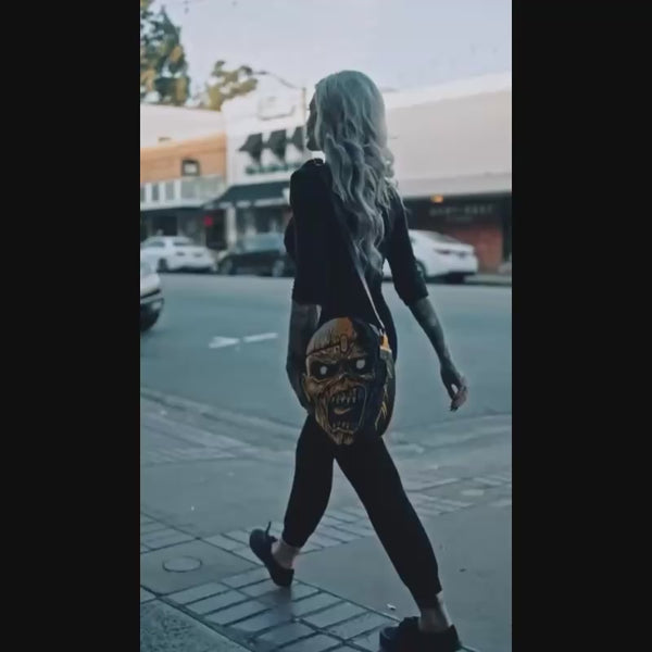 A woman walking while carrying Iron Maiden purse.