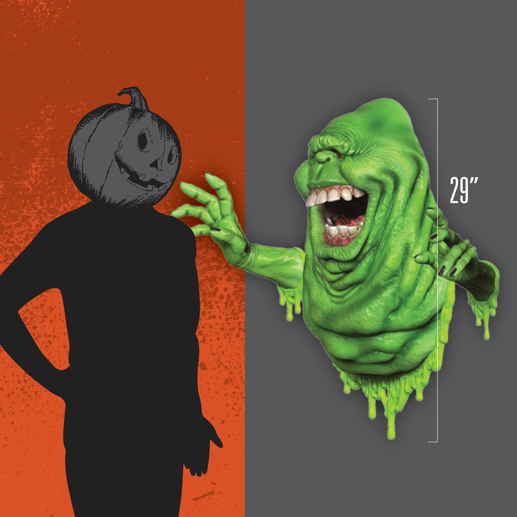 Orange and gray background. Person wearing black, gray jack o' lantern head, standing next to Wallbreaker to show size, 29 inches