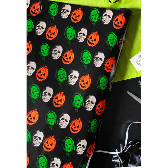 Wrapping paper. Black background with repeating pattern of orange jack o' lanterns, green witches and white skulls.