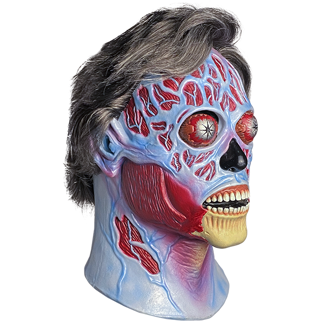 Mask, head and neck, right view. They Live Alien, short salt and pepper hair, blue and red skull like face, silver bulging eyes, black nose, mouth open, exposed teeth and bony chin.