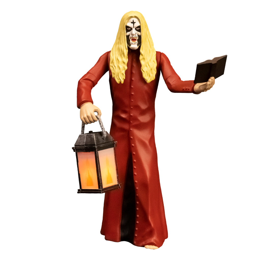 Action figure, front view.  Man, blond hair, white face with black cross on forehead, black around eyes, mouth and cheeks.  Wearing floor length red, button down coat, holding book in left hand, lantern in right hand.