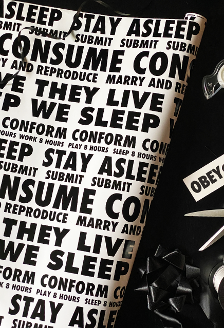 Wrapping paper.  White, with black repeating text that reads. Stay Asleep, Submit, Consume, Marry and Reproduce, They Live, We Sleep. Conform, Play 8 hours, Sleep 8 hours, Work 8 hours.