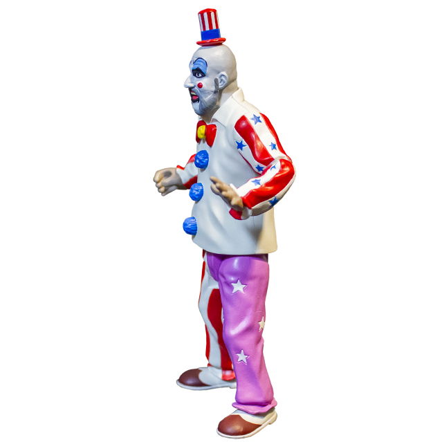 Captain Spaulding action figure, left side view. Bald man, red and white striped small top hat with blue band, white clown makeup, high black eyebrows, blue eyeshadow, black circles around eyes, pink spots on cheeks, large menacing grin, full gray beard, wearing white collared shirt, red and white striped sleeves with blue stars, red bow at collar, skull pin, blue pompoms, pants right leg red and white striped, left leg purple with white stars, brown and white shoes.