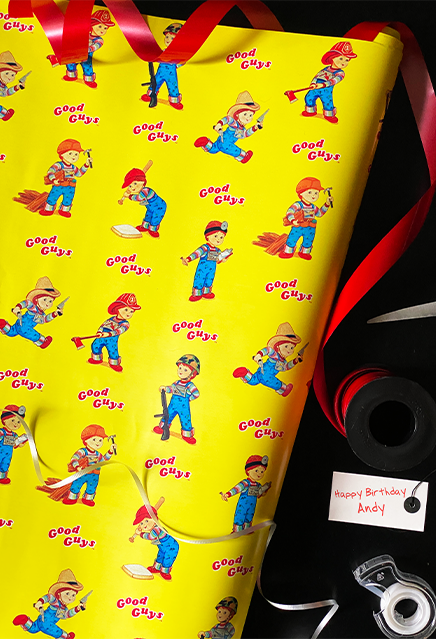 Wrapping paper roll, yellow background with illustrations of Good Guys dolls as Cowboy, fireman, soldier, construction worker, doctor and carpenter.  Next to paper is ribbon, tape and girft tag.