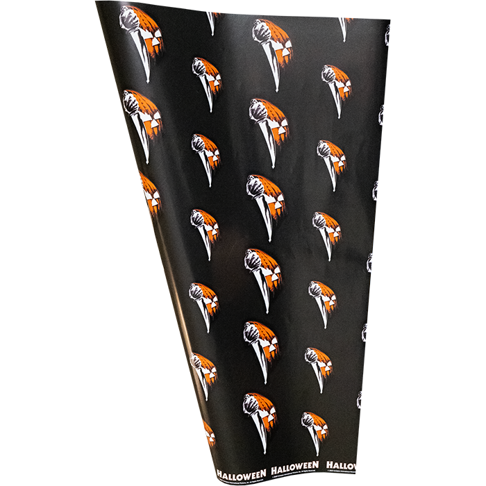 Wrapping paper.  Black background printed with orange jack o' lantern face and butcher knife pattern