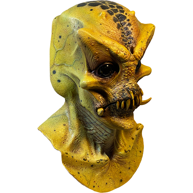 Mask, head neck and upper chest, right side view. Bald Alien head, black spots in center of crown of head. Large, pronounced brows and cheekbones. Large, shiny black eyes. No nose. Mouth with several sharp yellow teeth and two large tusks.