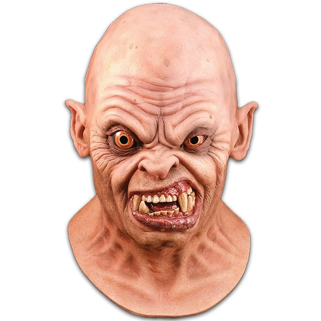 Front view.  Mask, head and neck.  Bald head, slightly pointed ears. Creased skin on forehead, around eyes and mouth.  Orange eyes, right eye bulging.  Snarling mouth with crooked teeth and large fangs.