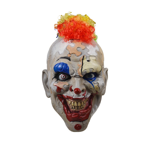 Front view.  Creepy clown face.  Skin made up of puzzle pieces, gray, white, beige, and peach.  Bright red clown mouth smiling with yellowed teeth.  Spiral right eye.  Rainbow curly mohawk hair.