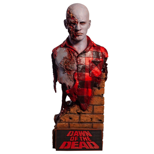 Front view.  Airport Zombie bust.  Head shoulders and upper torso.  Bald zombie,  right side of face and chest is gory, wearing torn red and black flannel shirt.  Base of bust is a broken brick wall, plaque at bottom, red text reads Dawn of the Dead.