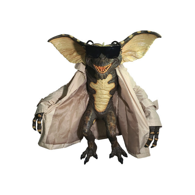 Gremlin Puppet, full view. Sharp teeth, black claws on hands and feet. Wearing black sunglasses and tan trench coat.